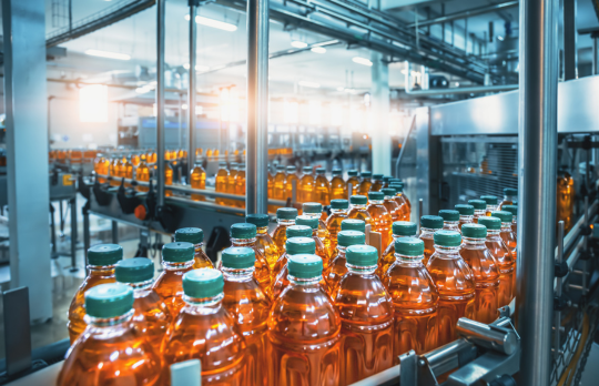 Une longue série de bouteilles en plastique se déplaçant le long d’une chaîne de production dans une usine