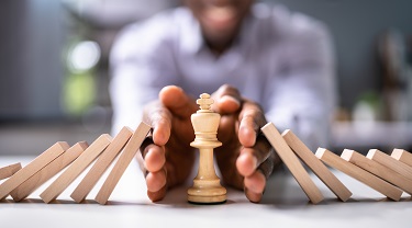 Les mains de l'homme bercent la pièce d'échecs alors que les dominos tombent