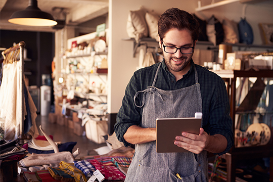 “A young male entrepreneur looks at his daily sales using a tablet”