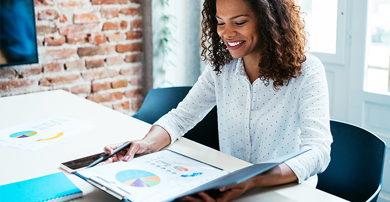 “A smiling businesswoman looks at a company’s monthly report”