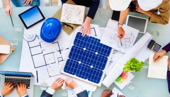 Cleantech company leaders look over blueprint drawings in office.