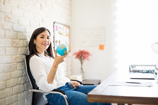 Young businesswoman in office holds globe
