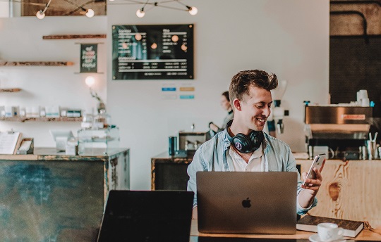 A young businessman checks out his new Shopify store on his mobile phone.