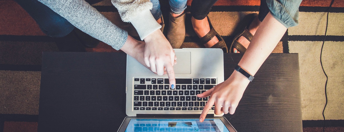 Three entrepreneurs gather excitedly around a laptop to see their new online store.