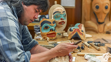An indigenous mask carver working in his shop.