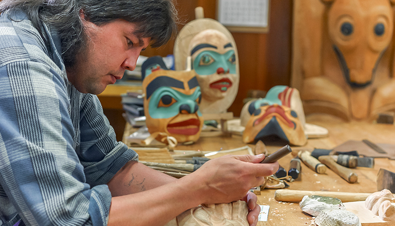 Un sculpteur autochtone travaille dans son atelier  à la création d’un masque.