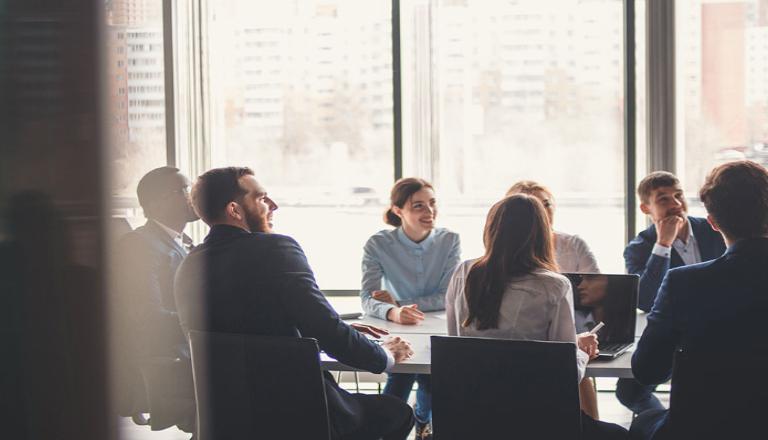 Employees collaborating at a board room table to be more competitive globally