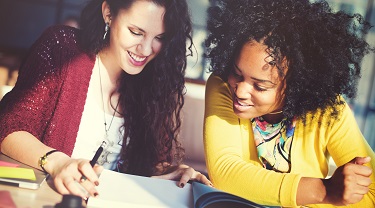 Two smiling women reading a report