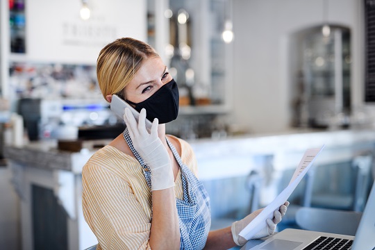 Woman at work on the phone wearing a mask, in a restaurant or bakery