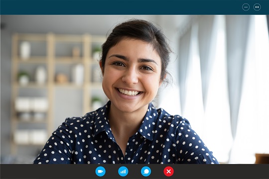 Femme qui suit un cours en ligne, souriant à l’écran