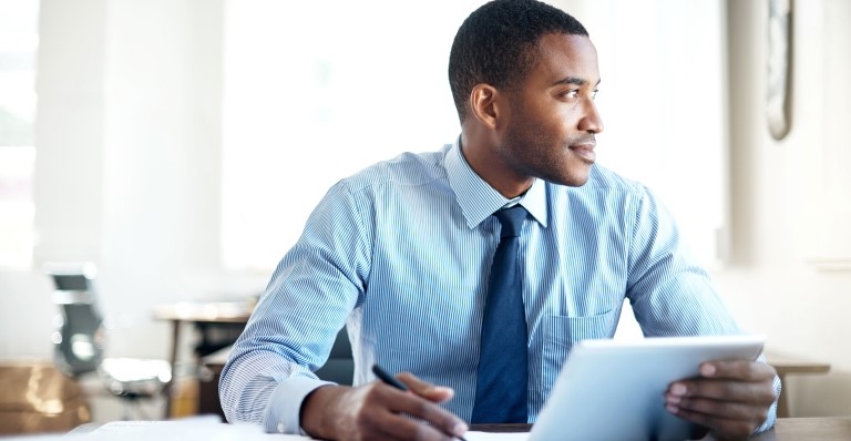 A man is working on his tablet but looking away