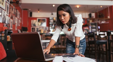 Female entrepreneur anxiously looks at computer