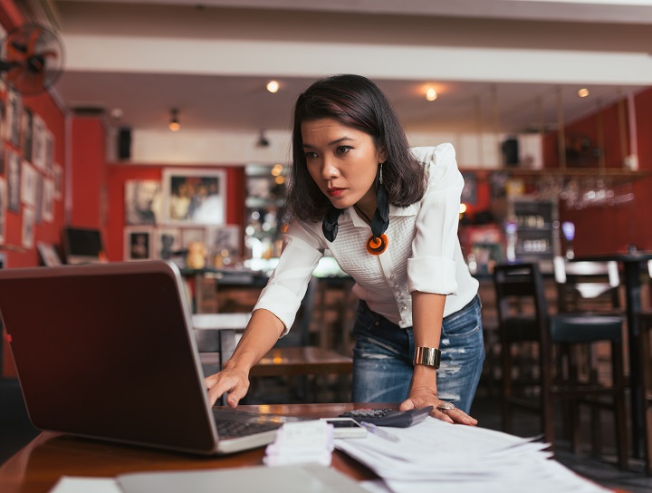 Female entrepreneur anxiously looks at computer