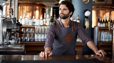 Pensive craft beer owner stands infront of bar