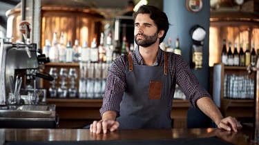 Le propriétaire d’une brasserie artisanale se tient pensif devant le bar de son établissement.