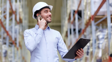 Man in hardhat with cellphone and clipboard