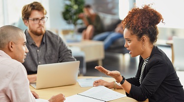 Deux hommes et une femme discutent de leur stratégie d’exportation dans un bureau