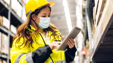 Asian-Canadian engineer checks details on warehouse tablet