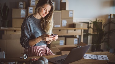 Une femme d’affaires au travail à son bureau consulte son cellulaire.