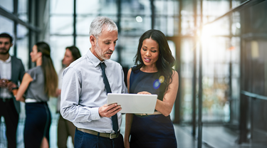 Female, male colleagues hold tablet and discuss business in office