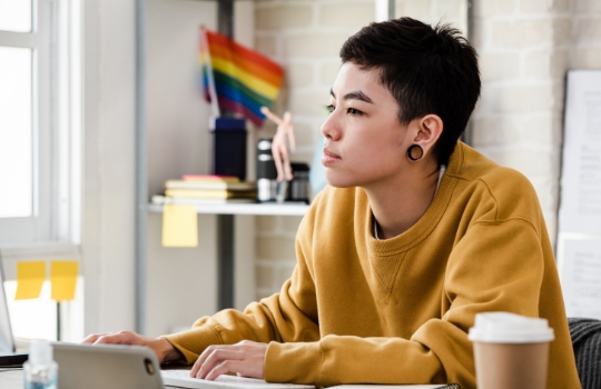 Young Asian non-binary person in casual attire working from home in living room
