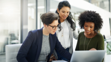 Three woman collaborating around a laptop