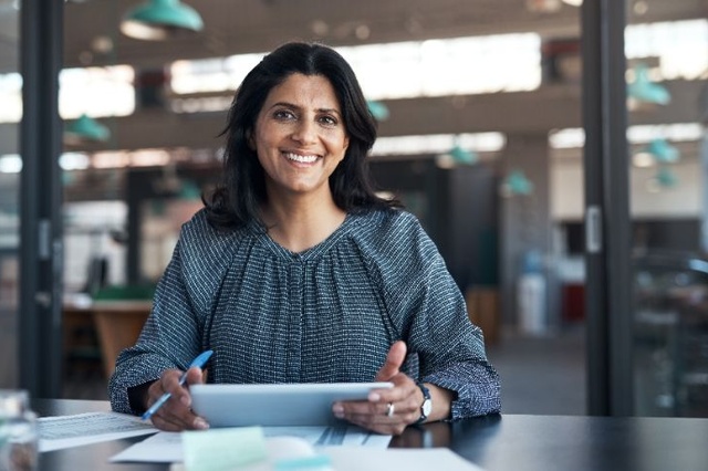 Femme dans un bureau tenant une tablette à un bureau.