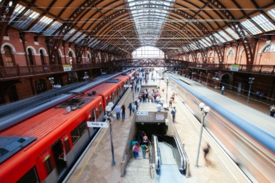 Une gare très fréquentée avec un train à l'arrêt et un autre flou à la sortie de la gare.