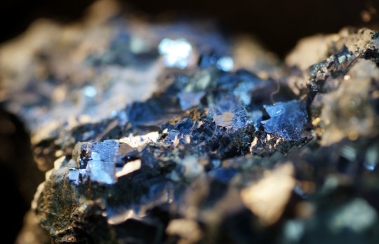 Gros plan sur des formations minérales incrustées dans la roche, dont les surfaces réfléchissantes captent la lumière