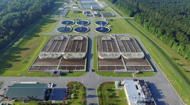 Aerial view of a water treatment plant surrounded by trees and green space.