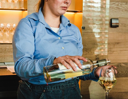 Femme remplissant un verre de vin blanc