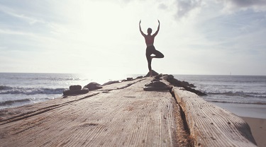 Woman doing yoga at the end of a dock.