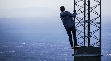 Man climbs up radio tower overlooking open water