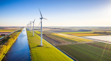 Des moulins à vent parsèment les terres agricoles avec un ciel bleu au bord d’une rivière