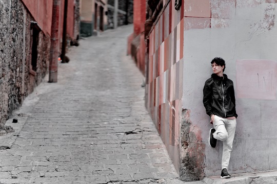 Man leaning against a brick wall.