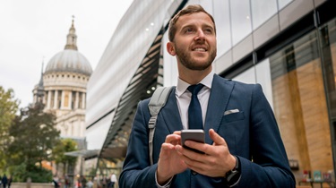 Businessman texts on phone with London, England, backdrop