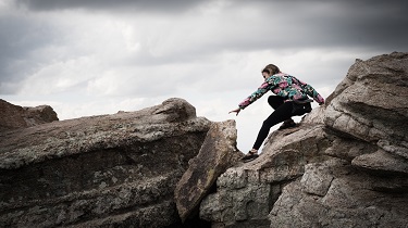 Une randonneuse fait une manœuvre risquée pendant son ascension entre deux rochers.