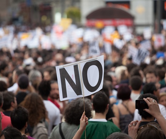 General mass protest with person holding “No” sign.