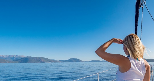 Woman peering across the water to the mountains in the distance