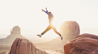 Man making a leap from one boulder to another