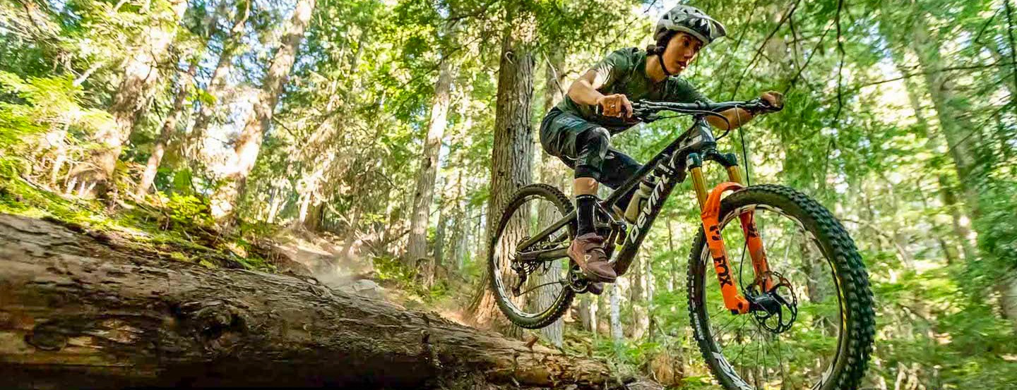 Une cycliste enthousiaste franchit une colline sur un vélo de montagne Devinci.