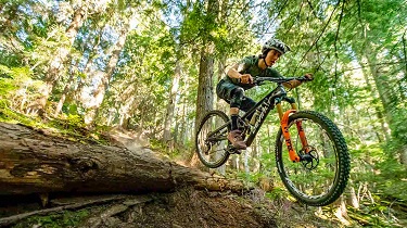 Une cycliste enthousiaste franchit une colline sur un vélo de montagne Devinci.