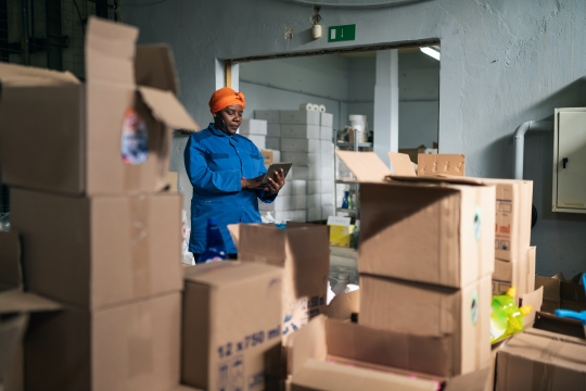 Female black business owner checking shipments in a distribution warehouse. 