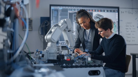 Male student engineer discussing ideas with black instructor while working with computer.