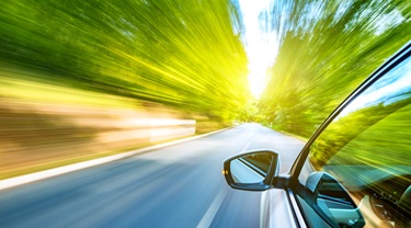 Racing car with blurred green trees on either side.