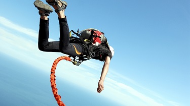 Man bungee jumping from the top of a cliff over a river