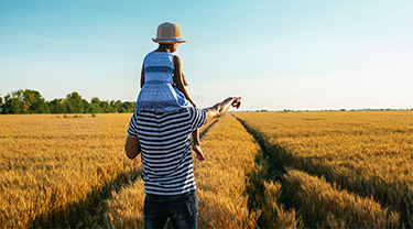 Dans un champ, un homme et une jeune fille pointent du doigt le paysage se trouvant devant eux