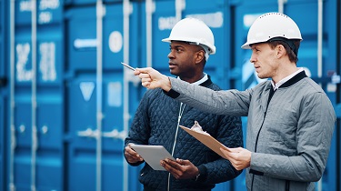 Deux exportateurs se tenant devant un conteneur discutent d’un chargement à expédier.