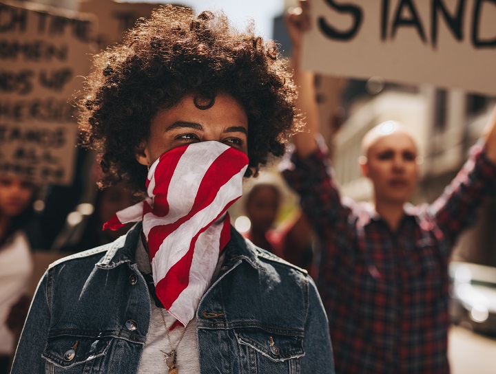 Femme portant le masque à la tête d’une manifestation.