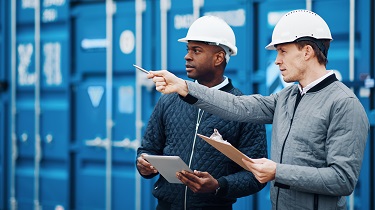 Deux exportateurs se tenant devant un conteneur discutent d’un chargement à expédier.